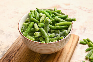 Bowl with frozen green beans on light background
