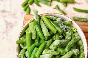 Bowl with frozen green beans on light background