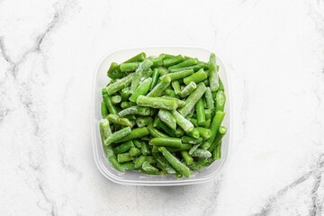 Container with frozen green beans on light background