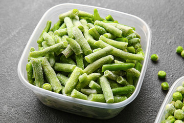 Container with frozen green beans on dark background