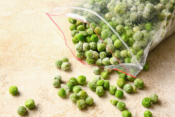 Bag with frozen green peas on light background