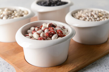 Bowls with different legumes on light background