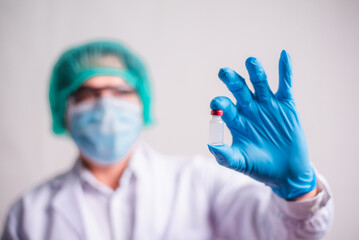 Doctor holding flu vaccine on beige background, medicine and drug concept. Vaccination against Coronavirus covid-19 pandemic.