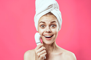 woman with towel on head naked shoulders skin care cosmetology pink background