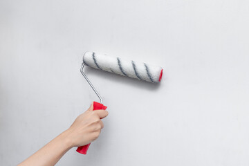 Applying primer and glue with a wide roller on the plastered surface of the wall for wallpapering