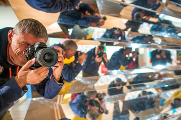 Photographer surrounded by mirrors. Reflection of man everywhere.