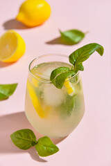 Glass of tasty lemonade with basil on color background