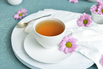 Cup with tasty floral tea on color background