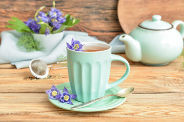 Composition with cup of floral tea and flowers on wooden background