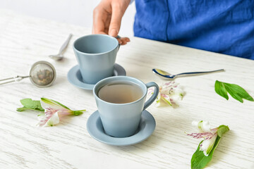 Woman with cups of floral tea on table