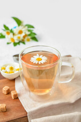 Composition with cup of floral tea and flowers on light background