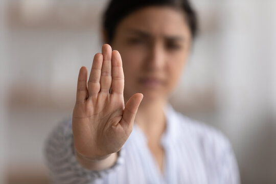 Close up focus on Indian woman showing stop gesture at camera, blurred background, strong young female protesting against domestic violence and abuse, bullying, saying no to gender discrimination