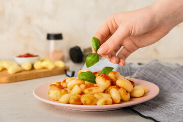 Woman decorating tasty gnocchi on plate