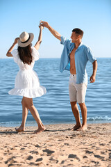 Happy young couple dancing on sea beach