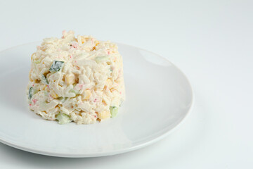 crab salad with rice on white plate closeup with copy space. Russian traditional salad with crab sticks isolated on white