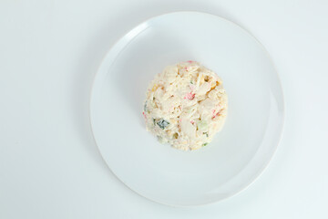 crab salad with rice on white plate closeup with copy space. Russian traditional salad with crab sticks isolated on white
