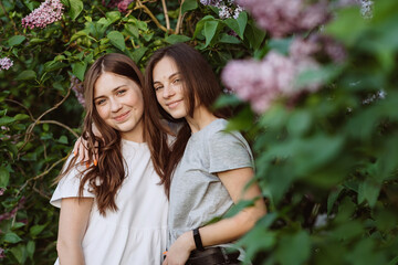 Two young happy teenage girls are resting in the park on the green grass. Female friendship. Soft selective focus.