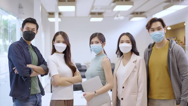 Portrait of Asian creative business team wears face mask. Hipster Creative Startup Young business people in modern office.