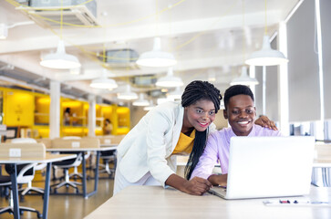 Portrait of a youthful black woman and guy smiling in a working environment with notebooks, African...