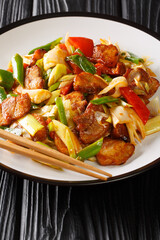 Twice cooked pork or double cooked pork is a Chinese dish include pork and stir-fried vegetables closeup in the plate on the wooden table. Vertical