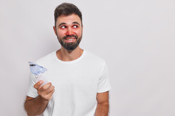 Happy man glad finally to breath by himself does inhalation through oxygen mask suffers from bronchial asthma looks away has allergic reaction isolated over white background copy space on right