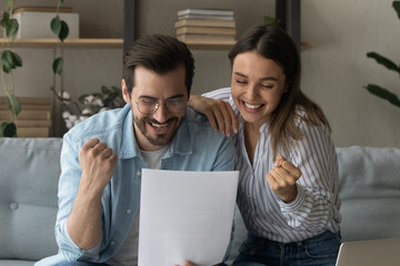 Beautiful couple read letter notification news from bank feel overjoyed clench fists make yes...