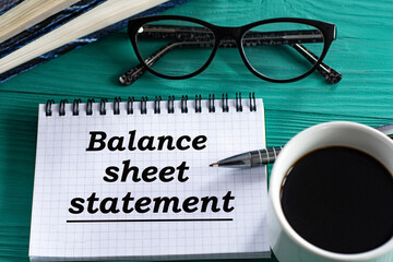 BALANCE SHEET STATEMENT - words in a notepad on a wooden green background with a calculator, pen and glasses
