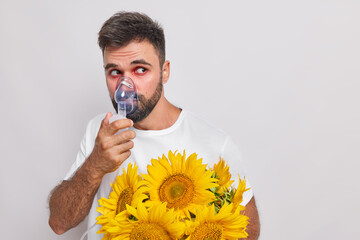 Allergic European man breathes through oxygen mask has allergy to sunflowers red watery eyes looks...
