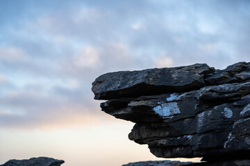 rocky stone consisting of several layers against the background of the sky - obrazy, fototapety, plakaty