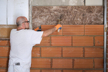 Builder laying bricks after placing an acoustic and thermal insulation.