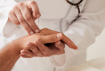 Reflexologist insert acupuncture needle into a patient's wrist hand. Acupuncture treatment,...
