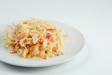 vitamin salad with carrot and cabbage closeup on white plate. fresh salad with sour cream isolated