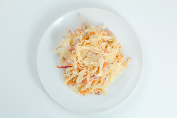 vitamin salad with carrot and cabbage closeup on white plate. fresh salad with sour cream isolated