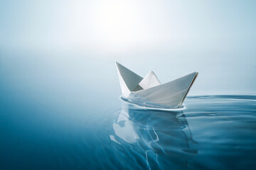 paper boat sailing on blue boundless water. - Powered by Adobe