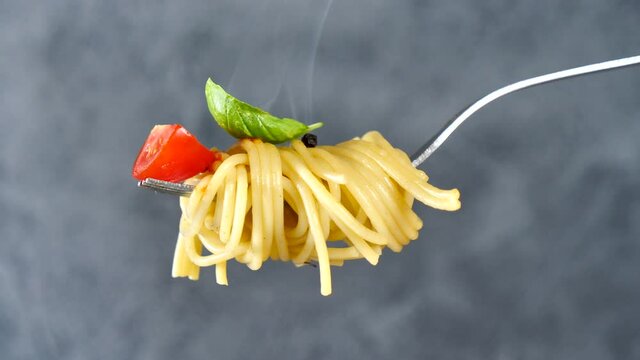 fork with spaghetti, tomato and basil with smoke