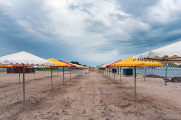 Cloudy sky over empty sandy beach and umbrellas. Bad weather at the resort
