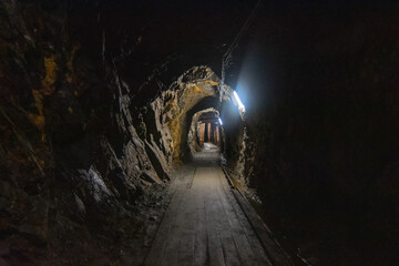 Naklejka premium Abandoned old coal mine interior. Dangerous tunnels full of dirt and rusty equipment. Metal and wooden timbering