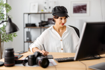 Attractive woman in stylish wear retouching photos at modern office. Female photographer using...