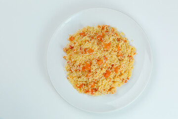 couscous with carrots in white plate closeup. couccous isolated on white background