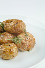 baked baby potatoe closeup on white plate. Roasted or baked baby potatoes with oil and herbs with white background