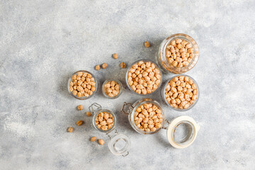 Uncooked dried chickpeas in different glass jars and bowls.