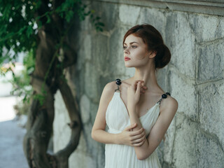 Obraz premium Woman in white dress near tree stone wall decoration lifestyle