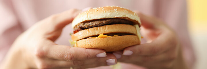 Female hands hold hamburger with cheese and meat