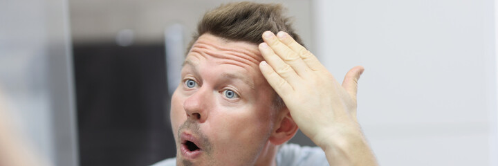 Narcissistic man in front of mirror does his hair