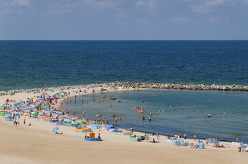 SEA COAST IN SUMMER - Holidaymakers relaxing on the sunny beach 
