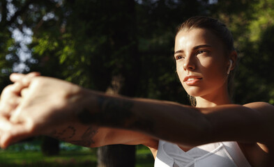 Close up of female runner with sporty body, stretching hands, fitness workout exercise outdoor....