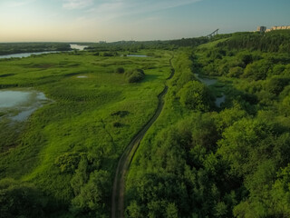 a winding dirt road passes through beautiful places through flowering fields past small lakes