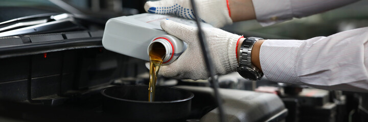 Foreman pours engine oil into engine closeup