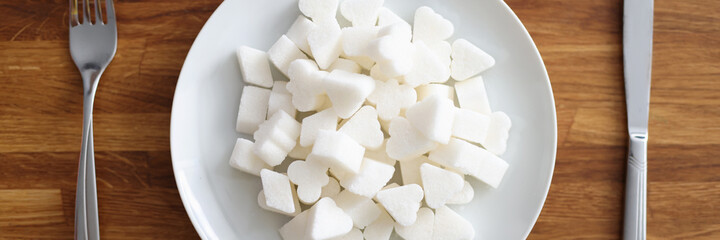 White sugar lies on plate next to fork and knife