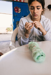 teenage girl learning to sew with green thread